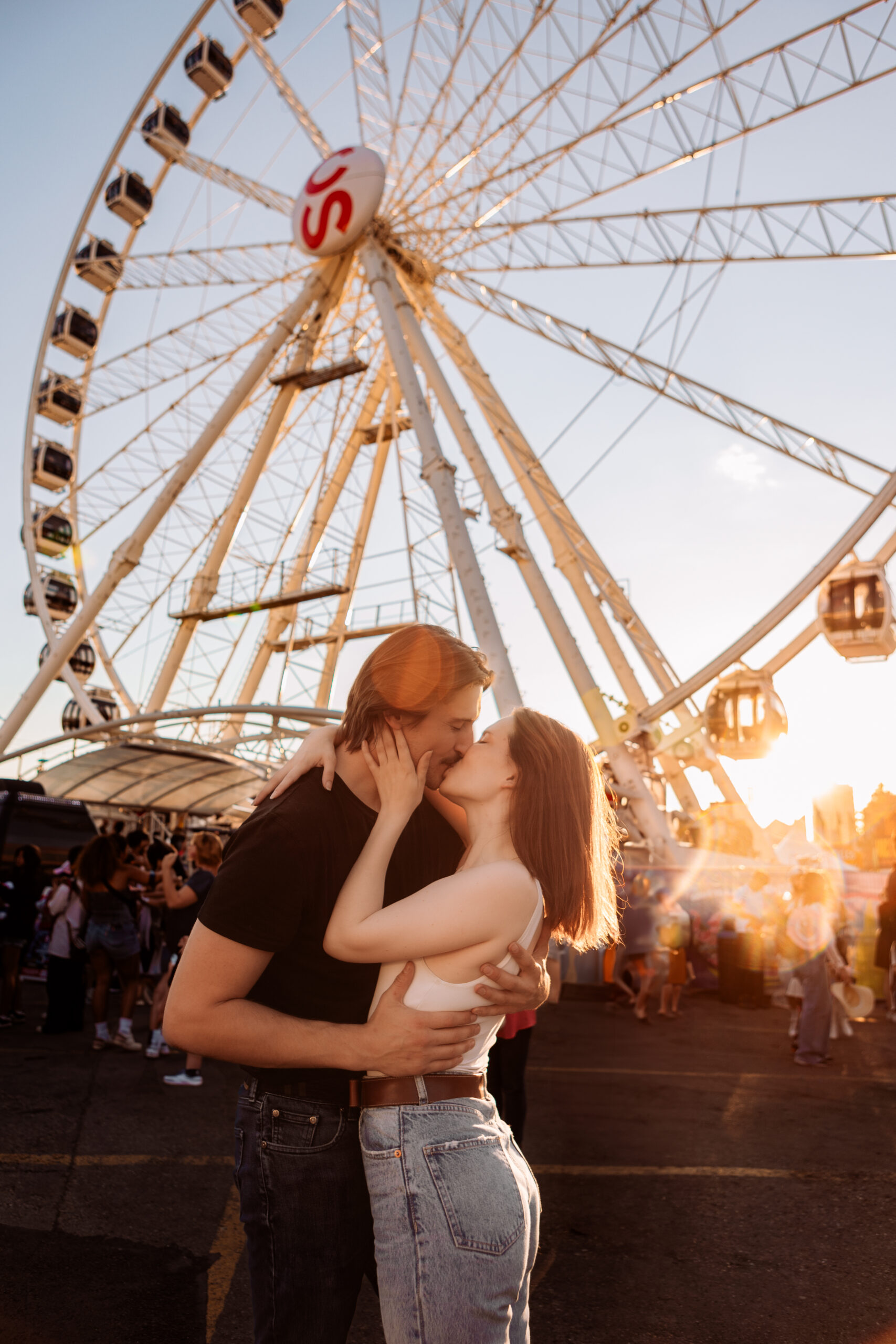 couple kissing at golden hour in front of a calgary stampede ferris wheel