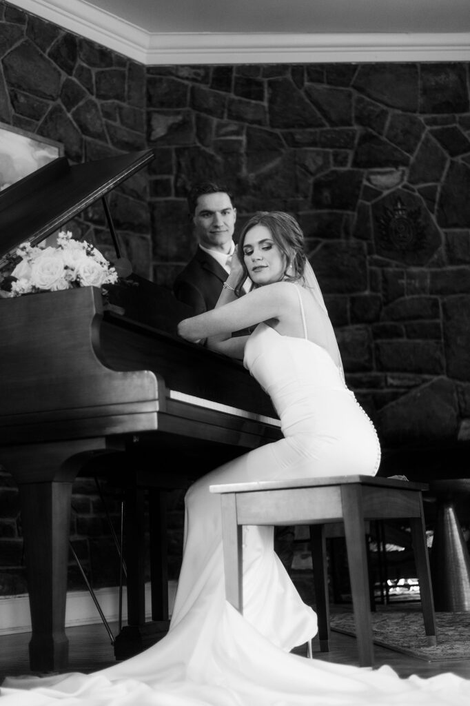 Calgary wedding photographer photograph of a bride sitting at a piano with her groom looking at her lovingly