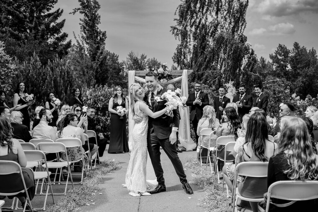 calgary wedding photographer photograph of a bride and groom smiling as they walk down the aisle after the ceremony