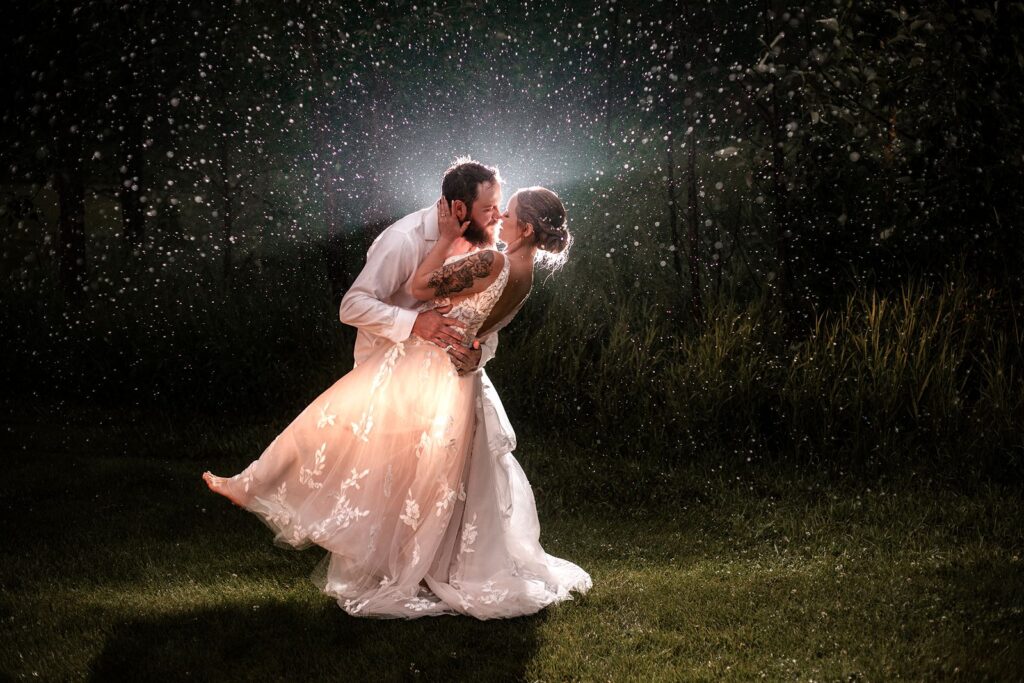 Calgary Wedding Photographer photograph of a bride and groom leaning in for a romantic kiss surrounded by rain