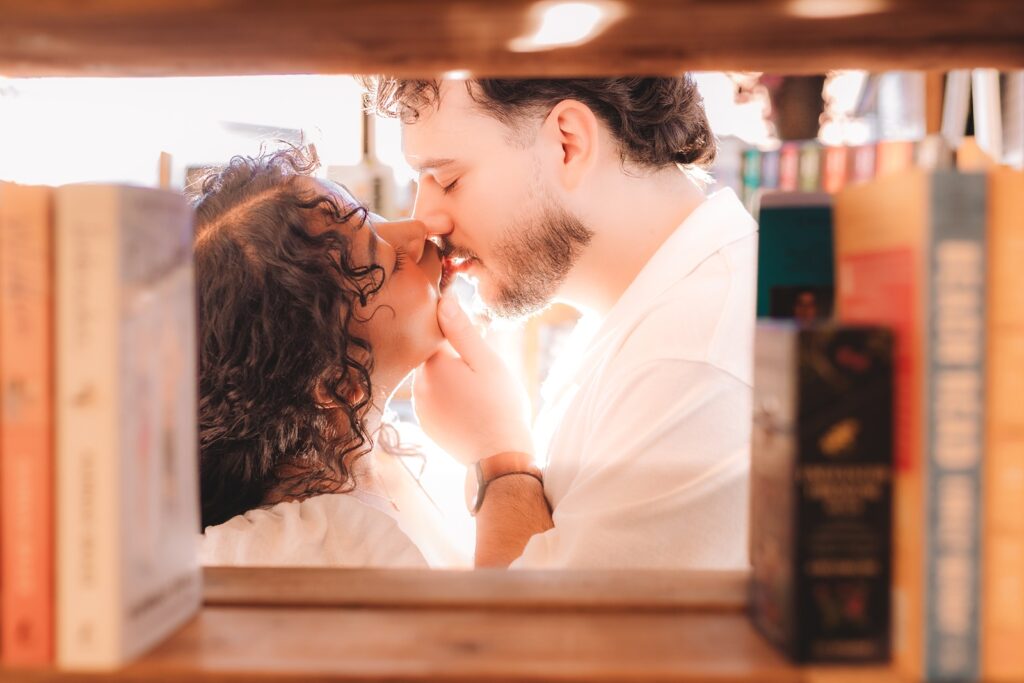 Couple kissing between books on a shelf at a Calgary Bookstore
