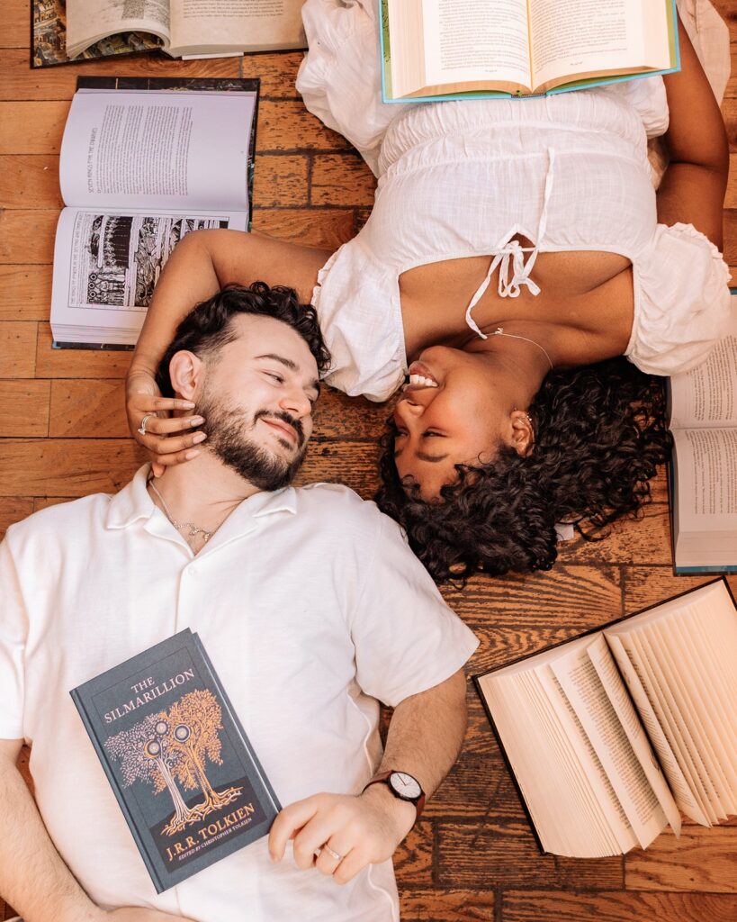 Couple laying on the ground surrounded by open books at Pages on Kensington