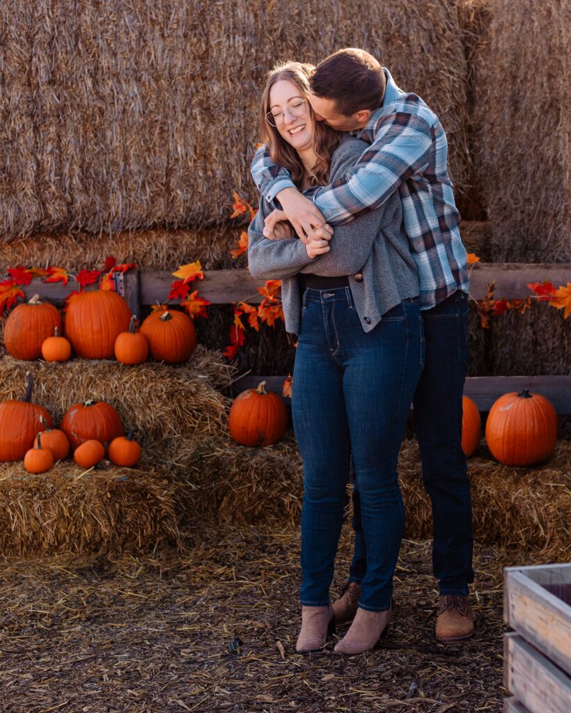 Couple snuggling up in a pumpkin patch