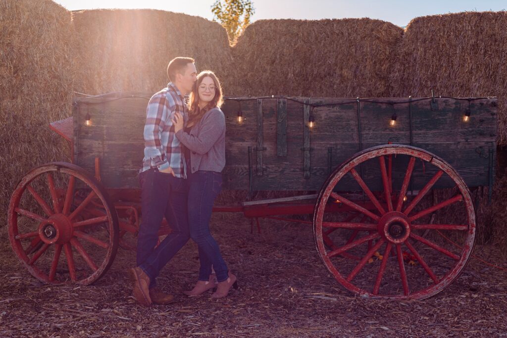 Couple posing in front of an old wagon