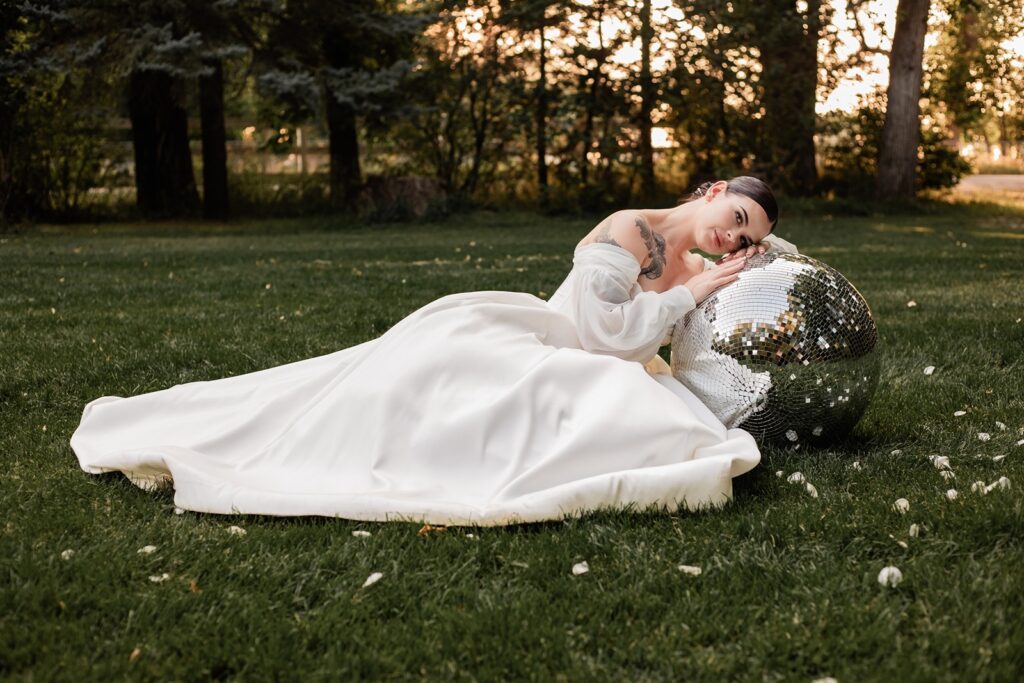 Bride leaning on a disco ball during golden hour