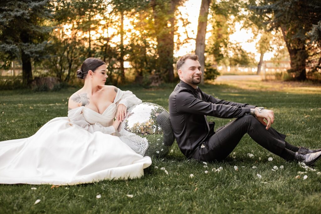 Bride and groom posing with a disco ball during golden hour