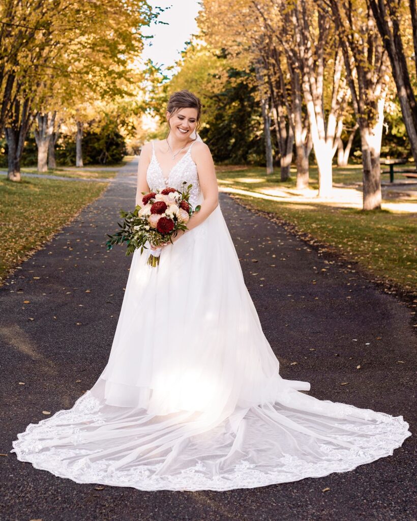 Bride poses on a path lined by autumn trees