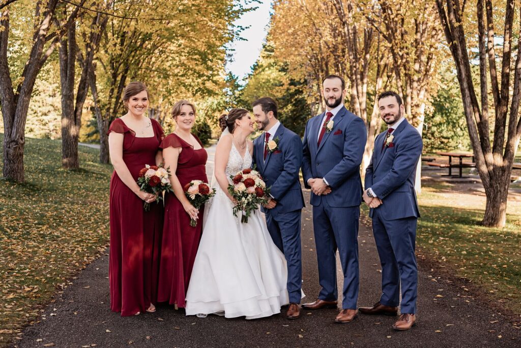 Bride and groom kiss in between their wedding party