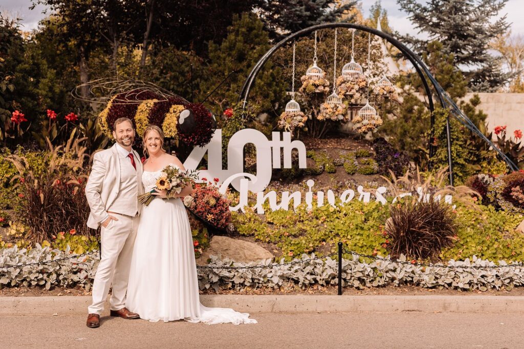 wedding couple posing beside topiary art that says "40th anniversary" 