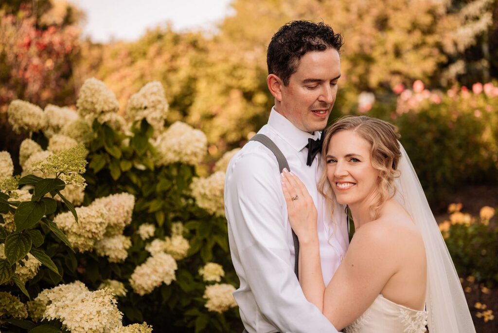 Groom and bride embracing in front of yellow flowers at the Calgary Zoo