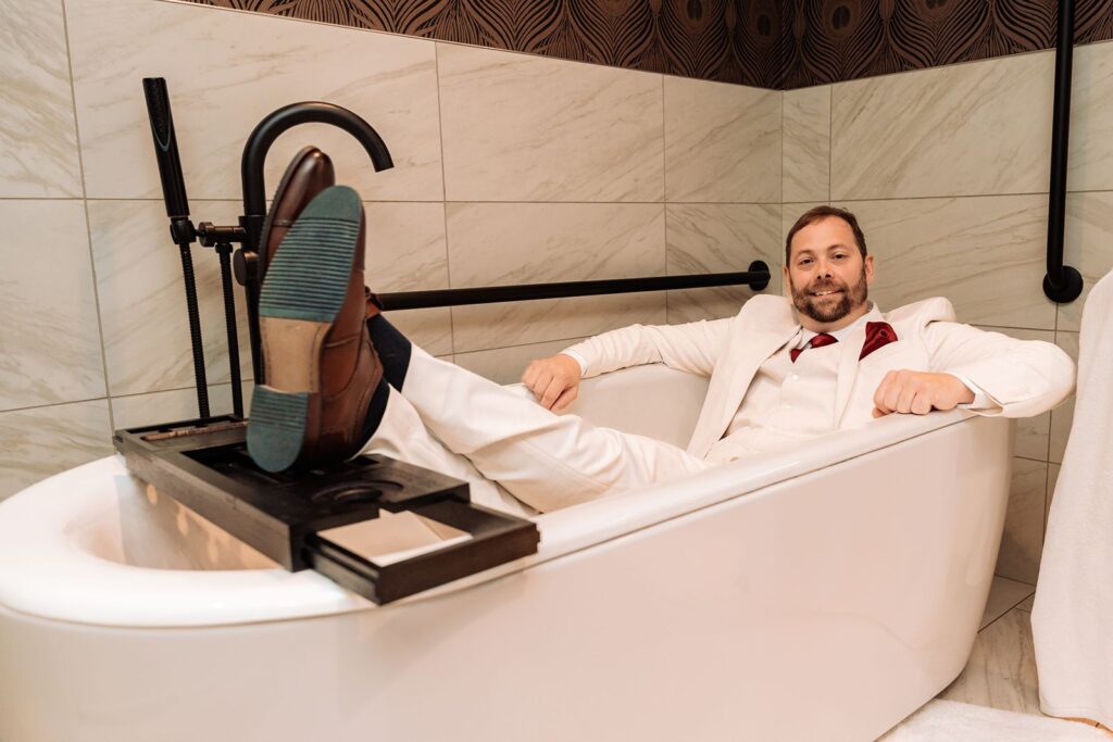 Groom sitting in a bathtub at The Dorian Hotel in Calgary