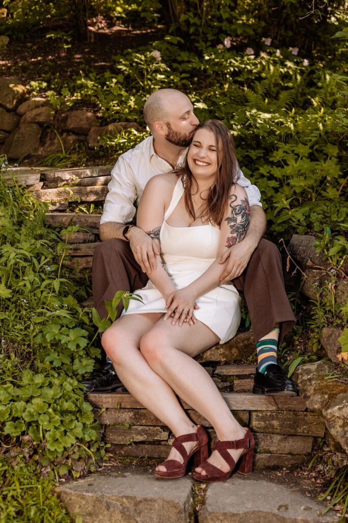 Engagement photo of a couple sitting on stone steps at Reader Rock Garden