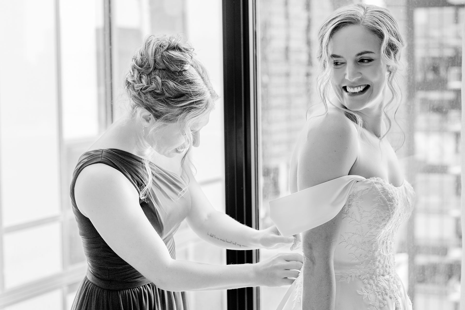 Maid of honor doing up buttons on brides dress