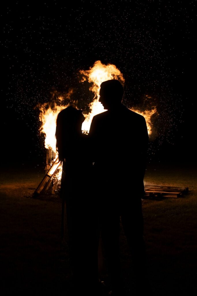 Silhouette of a couple in front of a large bonfire