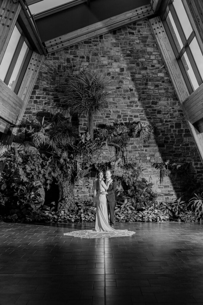 Bride and groom posing in front of a tree in the Calgary Zoo Conservatory lobby