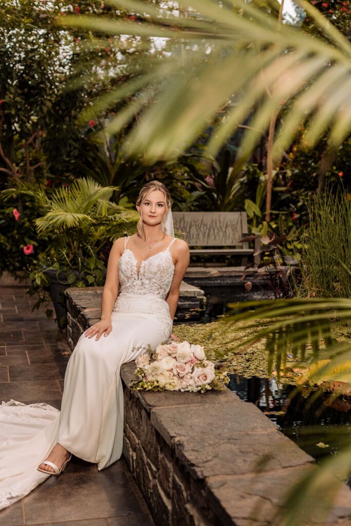 Bride sitting beside a pond in the Calgary Zoo Conservatory