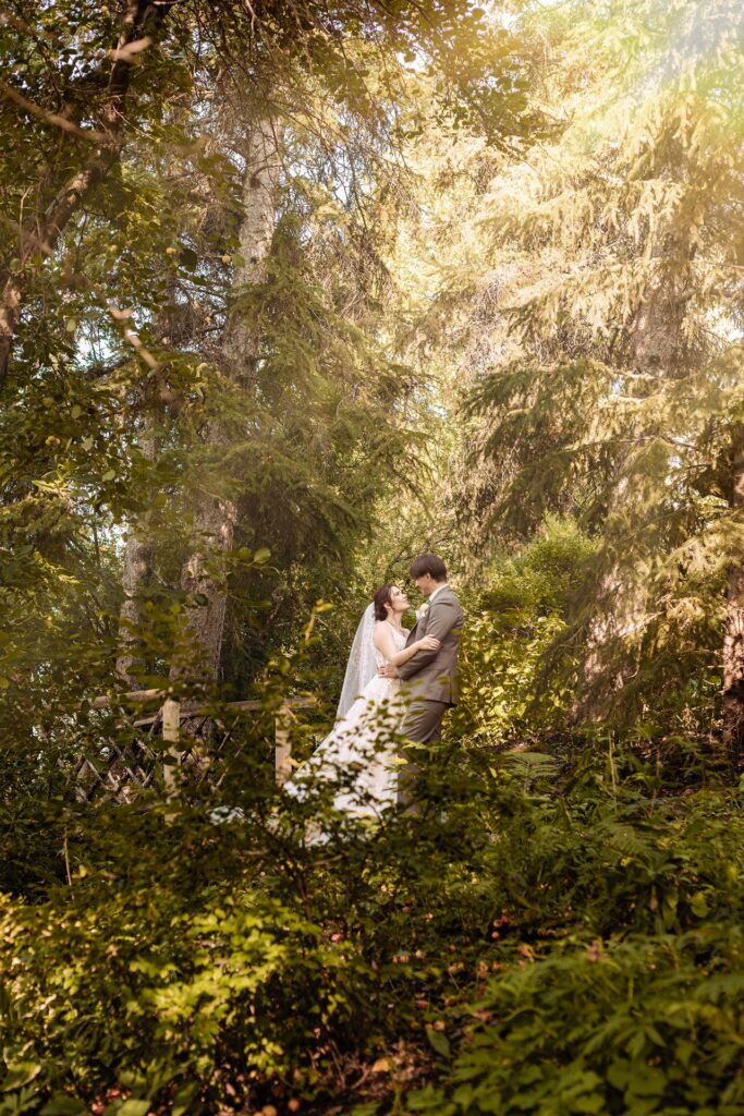Bride and groom embracing in a ray of sunshine during a garden wedding